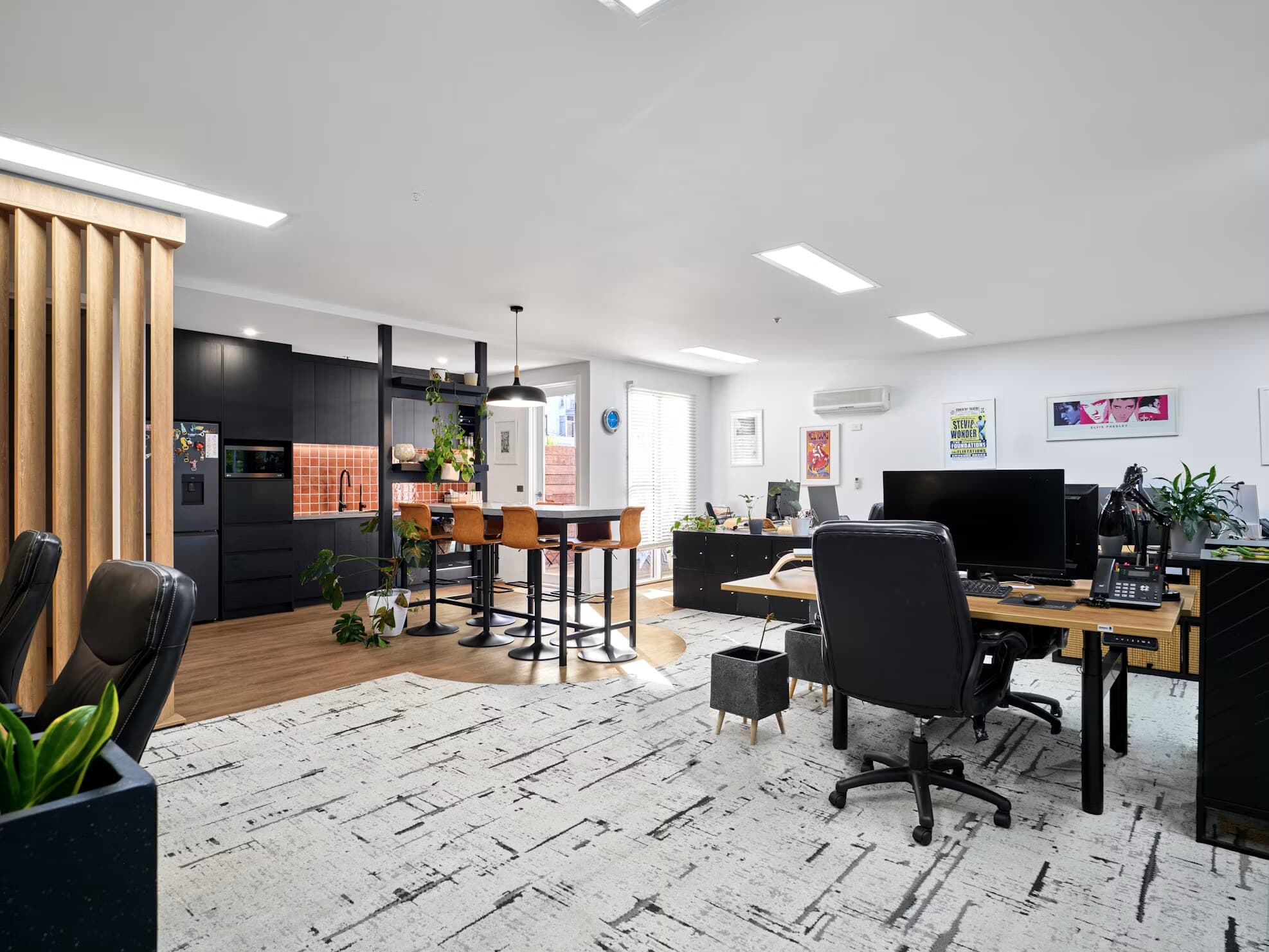 Open-plan office with a long work table and black task chairs